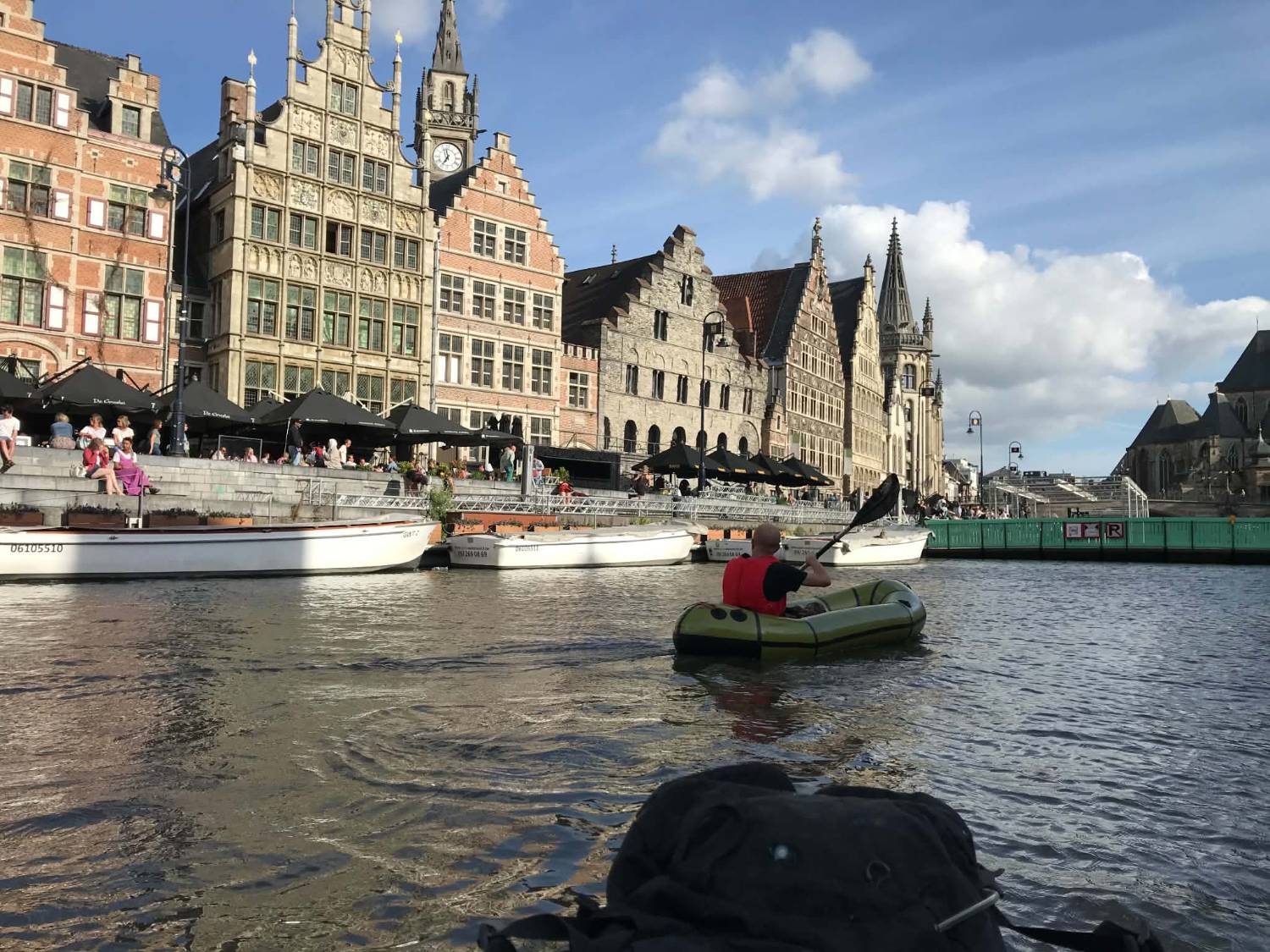Un packraft vert sur l'eau à Gand, devant les façades à pignons du centre historique
